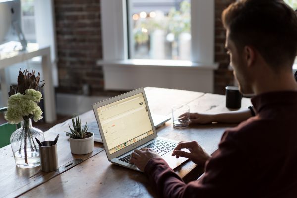 man typing on a macbook